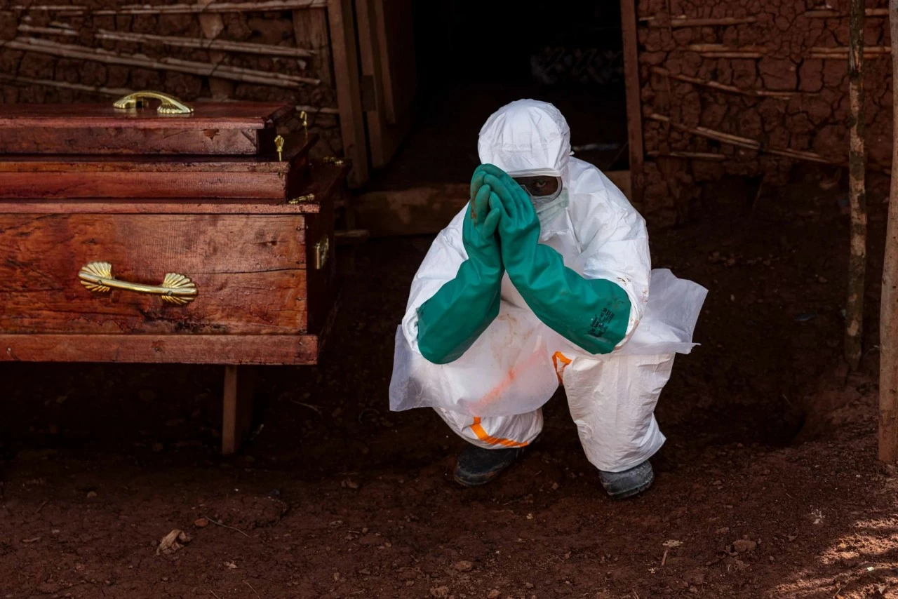 Một nhân viên y tế ngồi bên cạnh quan tài của một nạn nhân nghi mắc Ebola bên ngoài một ngôi nhà ở Mongbwalu, Democratic Republic of the Congo, hôm Chủ nhật, 24/5. Đợt bùng phát Ebola đang lan rộng nhanh chóng tại Cộng hòa Dân chủ Congo chỉ mới thu hút sự chú ý của thế giới hơn một tuần qua, nhưng hiện đã trở thành đợt bùng phát lớn thứ ba từng được ghi nhận. Theo World Health Organization (WHO), đợt dịch tập trung chủ yếu ở miền đông quốc gia châu Phi này đã khiến ít nhất 238 người tử vong và hơn 1.000 ca nghi nhiễm tính đến nay. Dịch bệnh do chủng Bundibugyo – một biến thể hiếm gặp của virus Ebola – gây ra, đồng thời đã lan sang nước láng giềng Uganda. Uganda ghi nhận ít nhất 7 ca liên quan đến ổ dịch, trong đó có một trường hợp tử vong. Ebola có thể gây tử vong ở khoảng 25% đến 90% số người mắc bệnh. Các nhà khoa học hiện đang khẩn trương nghiên cứu các loại vaccine và phương pháp điều trị mới nhằm kiểm soát đợt bùng phát này, tuy nhiên giới chức nhấn mạnh rằng hiện vẫn chưa có vaccine hoặc thuốc điều trị nào được phê duyệt đối với chủng virus đang gây dịch. (Nguồn: Getty Images) Một nhân viên y tế ngồi bên cạnh quan tài của một nạn nhân nghi mắc Ebola bên ngoài một ngôi nhà ở Mongbwalu, Democratic Republic of the Congo, hôm Chủ nhật, 24/5. Đợt bùng phát Ebola đang lan rộng nhanh chóng tại Cộng hòa Dân chủ Congo chỉ mới thu hút sự chú ý của thế giới hơn một tuần qua, nhưng hiện đã trở thành đợt bùng phát lớn thứ ba từng được ghi nhận. Theo World Health Organization (WHO), đợt dịch tập trung chủ yếu ở miền đông quốc gia châu Phi này đã khiến ít nhất 238 người tử vong và hơn 1.000 ca nghi nhiễm tính đến nay. Dịch bệnh do chủng Bundibugyo – một biến thể hiếm gặp của virus Ebola – gây ra, đồng thời đã lan sang nước láng giềng Uganda. Uganda ghi nhận ít nhất 7 ca liên quan đến ổ dịch, trong đó có một trường hợp tử vong. Ebola có thể gây tử vong ở khoảng 25% đến 90% số người mắc bệnh. Các nhà khoa học hiện đang khẩn trương nghiên cứu các loại vaccine và phương pháp điều trị mới nhằm kiểm soát đợt bùng phát này, tuy nhiên giới chức nhấn mạnh rằng hiện vẫn chưa có vaccine hoặc thuốc điều trị nào được phê duyệt đối với chủng virus đang gây dịch. (Nguồn: Getty Images)