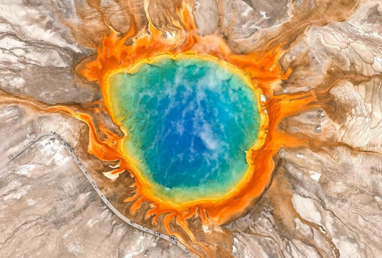 Bức ảnh chụp từ trên cao ngày Chủ nhật, 24/5, cho thấy du khách tham quan khu vực Grand Prismatic Spring nằm trong Yellowstone National Park. Đây là suối nước nóng lớn nhất nước Mỹ. Những dải màu rực rỡ bao quanh phần trung tâm màu xanh của suối được tạo nên bởi các vi sinh vật ưa nhiệt (thermophiles) — những sinh vật cực nhỏ phát triển mạnh trong môi trường nhiệt độ cao và xuất hiện phổ biến tại nhiều suối nước nóng ở Yellowstone. (Nguồn: Getty Images) Bức ảnh chụp từ trên cao ngày Chủ nhật, 24/5, cho thấy du khách tham quan khu vực Grand Prismatic Spring nằm trong Yellowstone National Park. Đây là suối nước nóng lớn nhất nước Mỹ. Những dải màu rực rỡ bao quanh phần trung tâm màu xanh của suối được tạo nên bởi các vi sinh vật ưa nhiệt (thermophiles) — những sinh vật cực nhỏ phát triển mạnh trong môi trường nhiệt độ cao và xuất hiện phổ biến tại nhiều suối nước nóng ở Yellowstone. (Nguồn: Getty Images)