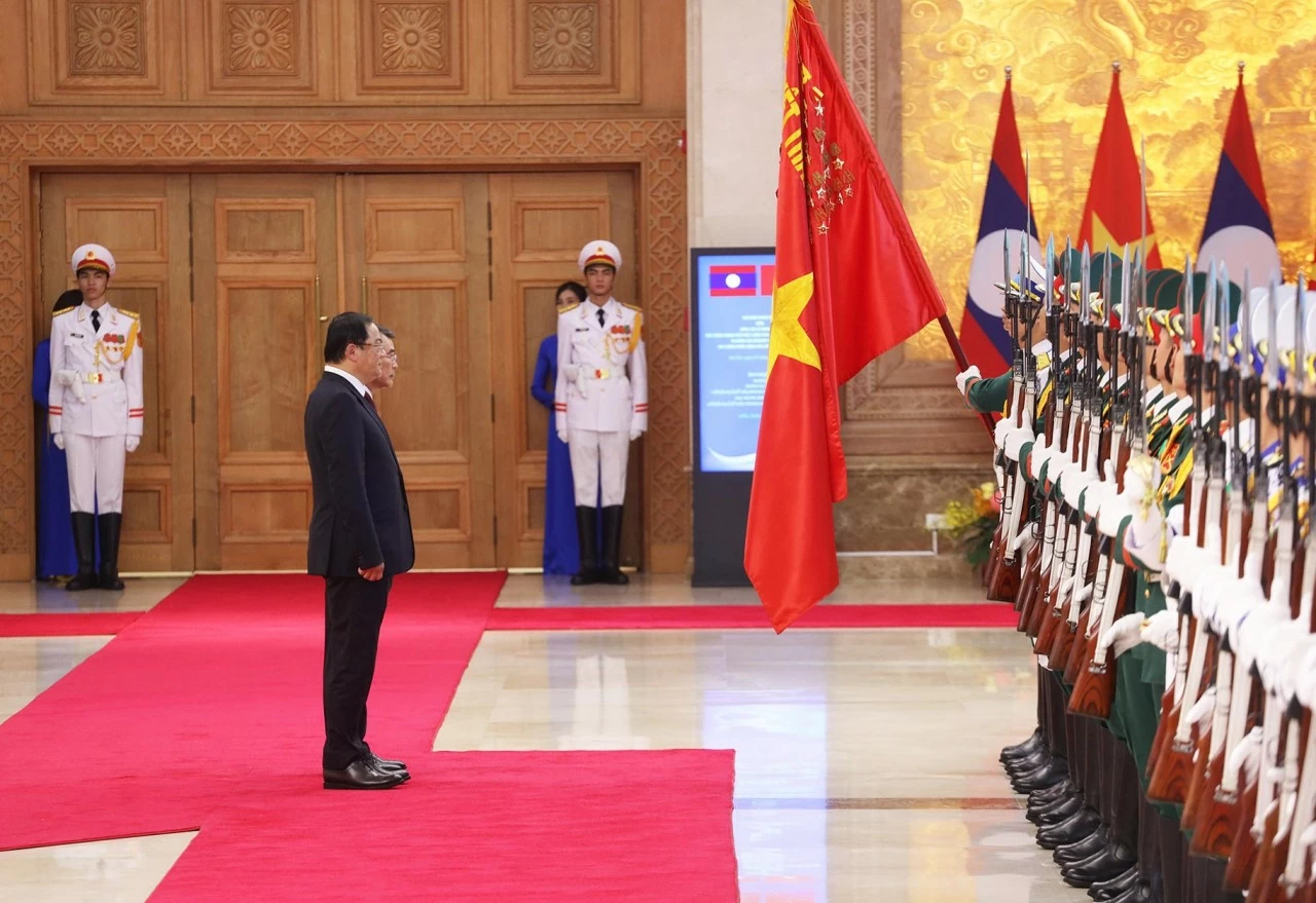 Thủ tướng Chính phủ Lê Minh Hưng và Thủ tướng Lào Sonexay Siphandone cúi chào Quân kỳ Quyết thắng. (Ảnh: Thành Long)