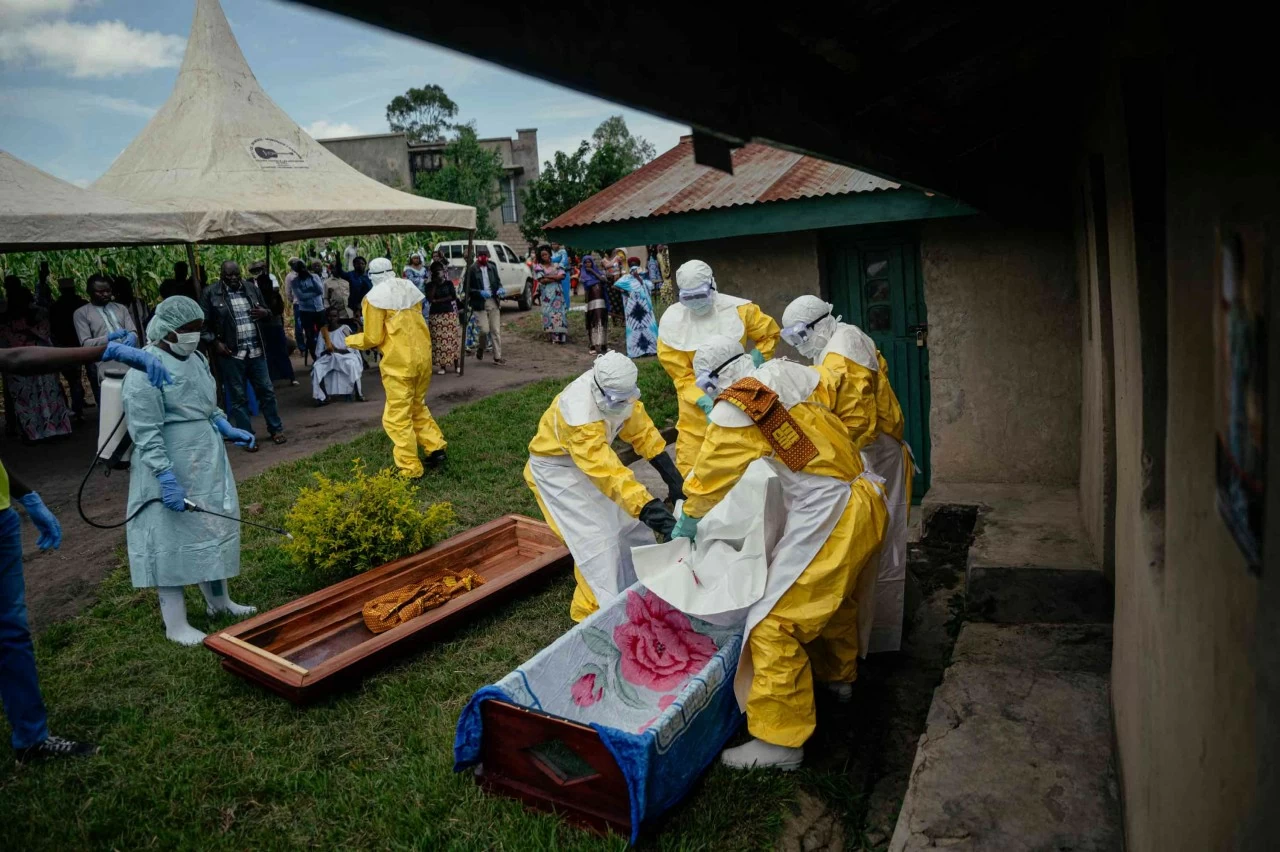 Các thành viên của đội Chữ thập đỏ Congo khiêng thi thể một phụ nữ nghi tử vong do Ebola, đặt vào quan tài trước khi tiến hành an táng an toàn tại nhà riêng của bà trong thành phố. Theo một phân tích của các quan chức y tế Mỹ, đợt bùng phát Ebola tại khu vực Trung Phi hiện nay có nguy cơ lan rộng với quy mô tương đương đợt dịch tồi tệ nhất trong lịch sử ở Tây Phi giai đoạn 2014–2016, vốn đã cướp đi sinh mạng của hơn 11.000 người. (Nguồn: Getty Images)