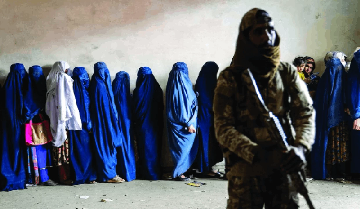 Một tay súng Taliban đứng gác khi phụ nữ chờ nhận hàng cứu trợ tại Kabul. Liên hợp quốc đang kêu gọi chính quyền Taliban nới lỏng các biện pháp hạn chế đối với phụ nữ trong bối cảnh lo ngại về tình hình nhân quyền tại Afghanistan gia tăng. (Ảnh: The Pioneer)