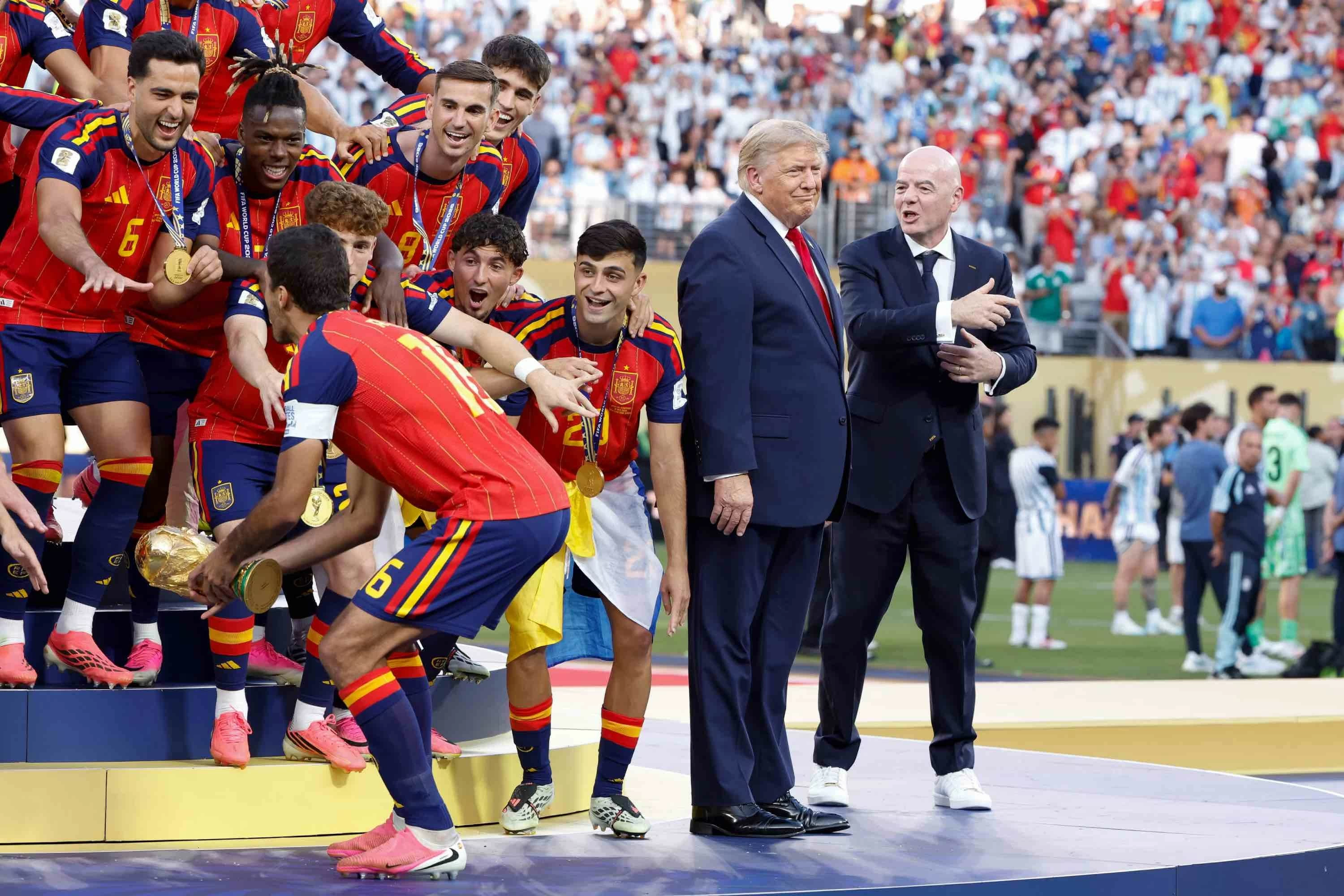 Spain giành chức vô địch FIFA World Cup khi đội trưởng Rodri nâng cao chiếc cúp, trong lúc Donald Trump và Chủ tịch Gianni Infantino đứng trên sân khấu tại sân vận động New York New Jersey. Ông Trump và ông Infantino đã bị một bộ phận khán giả la ó khi bước xuống sân để tham dự lễ trao giải, trước khi Tổng thống Mỹ bị cho là đã cố chen vào màn ăn mừng chiến thắng của đội tuyển Tây Ban Nha. (Nguồn: Getty Images) Spain giành chức vô địch FIFA World Cup khi đội trưởng Rodri nâng cao chiếc cúp, trong lúc Donald Trump và Chủ tịch Gianni Infantino đứng trên sân khấu tại sân vận động New York New Jersey. Ông Trump và ông Infantino đã bị một bộ phận khán giả la ó khi bước xuống sân để tham dự lễ trao giải, trước khi Tổng thống Mỹ bị cho là đã cố chen vào màn ăn mừng chiến thắng của đội tuyển Tây Ban Nha. (Nguồn: Getty Images)