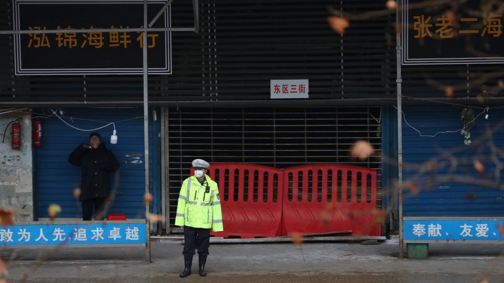 Một sĩ quan cảnh sát đứng trước chợ thủy sản có liên quan đến đợt bùng phát virus corona ở Vũ Hán, Trung Quốc vào tháng 1 năm 2020. © Reuters