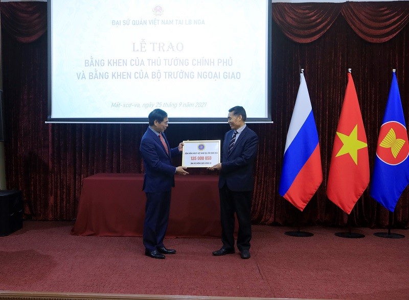 Bộ trưởng Bộ Ngoại giao Bùi Thanh Sơn (bên trái) tiếp nhận tượng trưng số tiền 135.000 USD do Hội người Việt Nam tại Liên bang Nga quyên góp, ủng hộ đồng bào trong nước phòng, chống dịch Covid-19. (Nguồn: TTXVN)