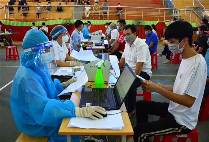 Bàn đăng ký, khai báo y tế cho người dân trước khi tiêm phòng COVID-19 tại nhà thi đấu huyện Hải Hậu, Nam Định. (Nguồn: TTXVN)