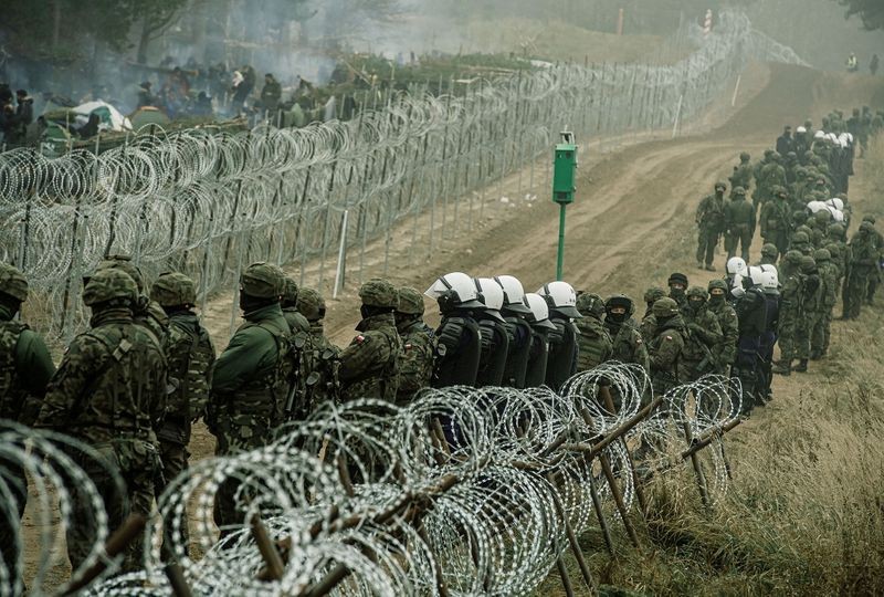 Cảnh sát và binh lính Ba Lan quan sát người di cư tại biên giới Ba Lan-Belarus gần Kuznica, Ba Lan ngày 12/10. (Nguồn: Reuters)