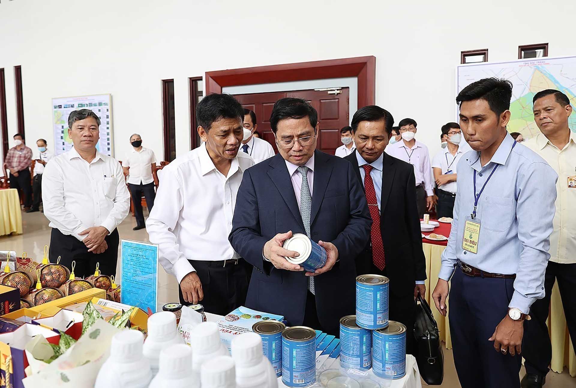 Thủ tướng Phạm Minh Chính xem sản phẩm trưng bày tại hội nghị. (Nguồn: TTXVN)