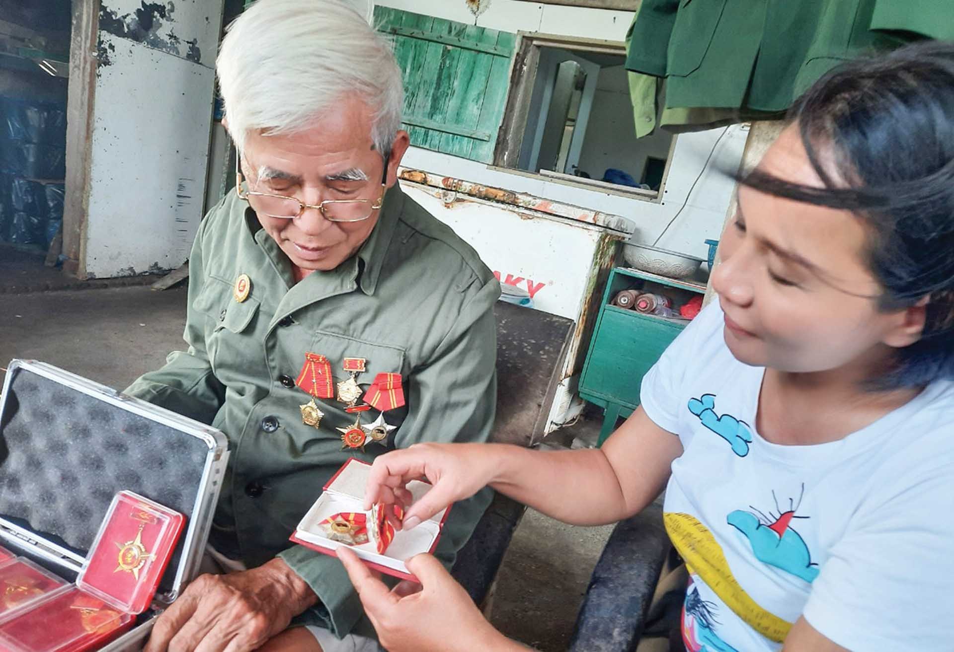 Tác giả và nhân vật bên những kỷ vật những huân huy chương được Đảng và Nhà nước trao tặng. (Ảnh: Hạnh Mi)