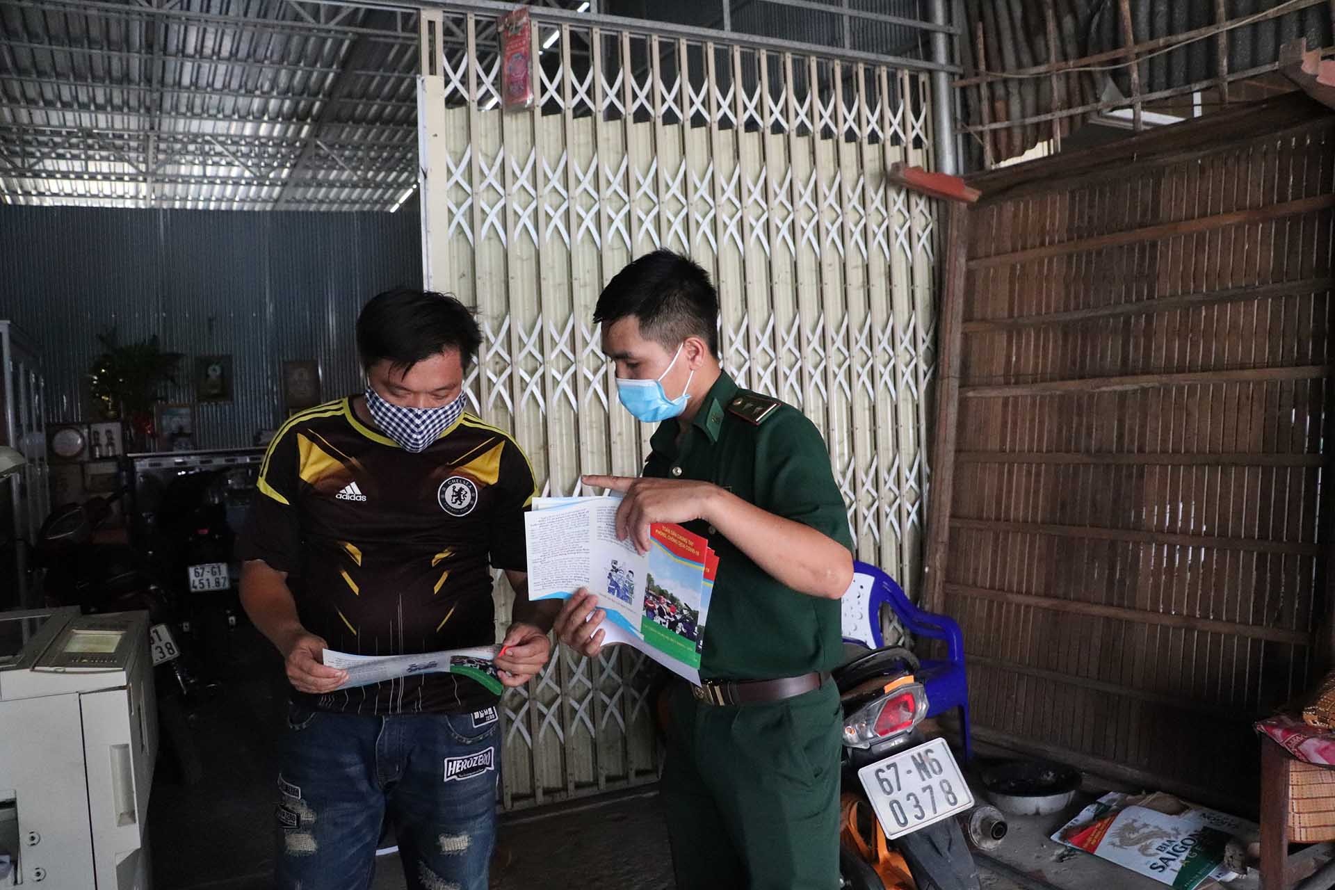 Cán bộ Đồn Biên phòng cửa khẩu Long Bình phát tờ rơi tuyên truyền phòng, chống dịch Covid-19. (Ảnh: Chiến Khu)