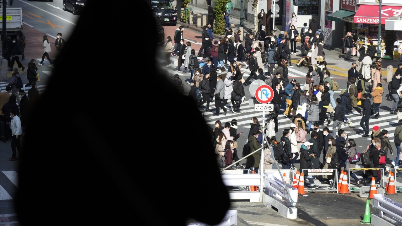 People wearing protective masks to help curb the spread of the coronavirus walk along a pedestrian crossing Friday, Jan. 21, 2022, in Tokyo. (AP Photo/Eugene Hoshiko)