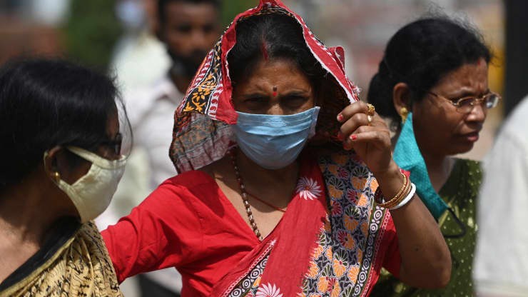 Một phụ nữ đeo mặt nạ để đề phòng Covid-19 đứng trong khu vực đông đúc gần Cổng Ấn Độ, ở New Delhi vào ngày 19 tháng 3 năm 2021 khi các trường hợp nhiễm coronavirus tiếp tục gia tăng trên khắp Ấn Độ.