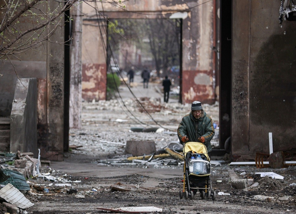 (04.17) Ukraine cho biết đã tạm dừng hành lang nhân đạo trong một ngày vì không đạt thỏa thuận với Nga - Ảnh: Một người dân Ukraine di chuyển trong đống đổ nát tại thành phố Mariupol. (Nguồn: TASS)