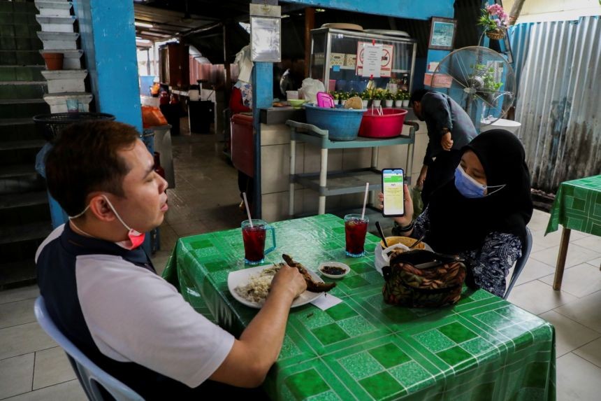 (09.26) Một người dân trình chứng nhận tiêm chủng vaccine Covid-19 để vào nhà hàng tại Malaysia. (Nguồn: Reuters)