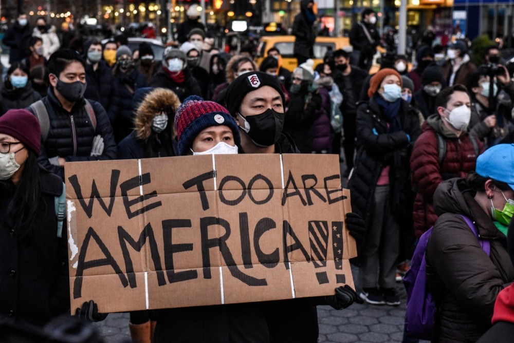 Một phụ nữ cầm biểu ngữ ghi thông điệp Mỹ thông qua dự luật để hạn chế tội ác gia tăng nhằm vào cộng đồng người Mỹ gốc Á