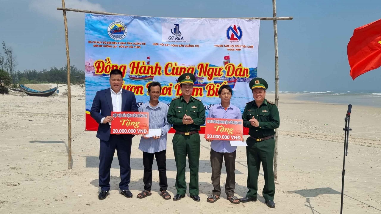 Đại tá Đinh Xuân Hùng, Chính ủy BĐBP Quảng Trị ( thứ nhất từ trái sang)  trao cờ Tổ quốc cho các ngư dân thôn Đông Luật. (Ảnh: Phước Trung)