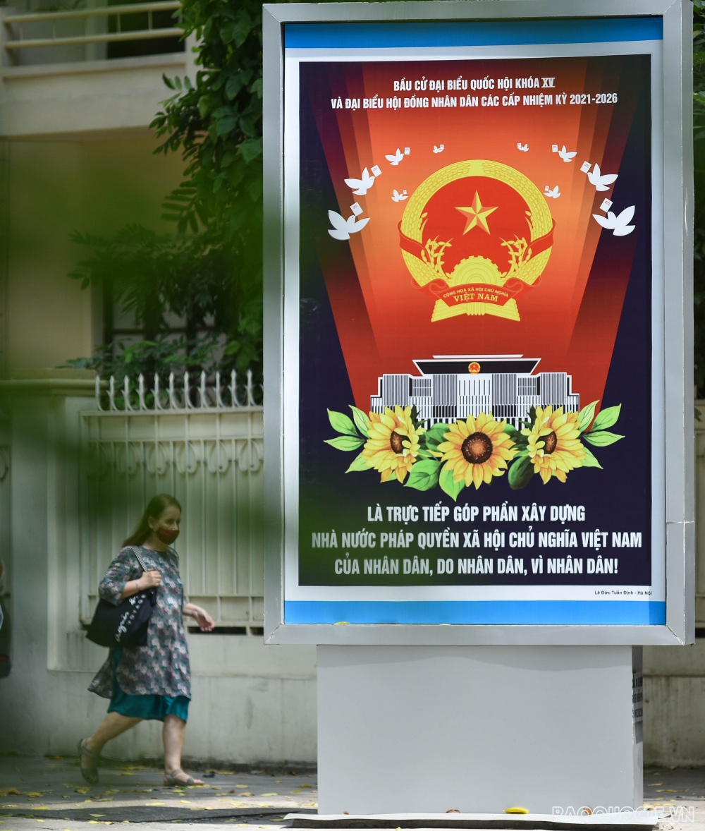 Tấm pano với khẩu hiệu; Bầu cử Đại biểu Quốc hội khóa XV và đại biểu hội đồng nhân dân các cấp nhiệm kỳ 2021-2026 là trực tiếp góp phần xây dựng Nhà nước pháp quyền xã hội chủ nghĩa Việt Nam của nhân dân, do nhân dân, vì nhân dân!