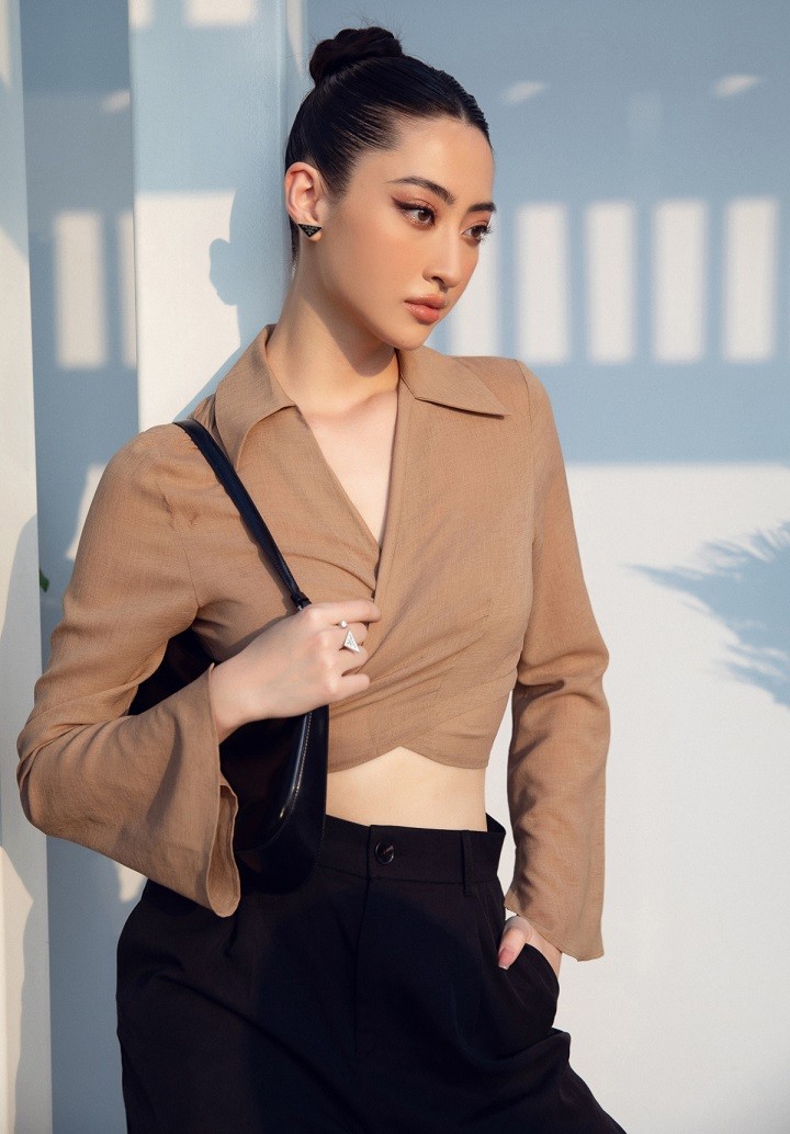 Hoa hậu Lương Thùy Linh kết hợp quần tây và áo crop-top dài tay, tóc búi cao gọn gàng trông như một quý cô công sở.