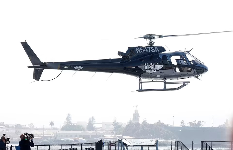 Tom Cruise xuất hiện trên chiếc trực thăng màu đen in dòng chữ 'Tom Cruise Top Gun: Maverick'. Tom đã có kinh nghiệm lái máy bay hàng chục năm và sở hữu phi cơ riêng. Nam diễn viên cũng nổi tiếng với những màn trình diễn nguy hiểm trên bầu trời trong các phim hành động bao gồm 'Top Gun' và 'Nhiệm vụ bất khả thi'.