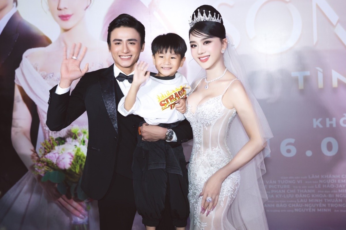 Diễn viên Song Duy (trái) giúp Lâm Khánh Chi ẵm bé Thiên Long. Ca sĩ cho biết cô chuẩn bị sẵn vest cho con trai nhưng bé bị sốt nhẹ sát giờ họp báo nên cô để con mặc trang phục thoải mái. Cậu nhóc bốn tuổi tỏ ra háo hức bởi đây là lần hiếm hoi theo mẹ dự sự kiện.