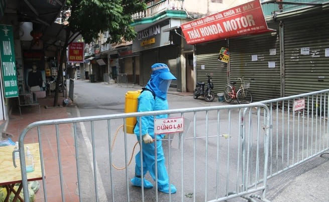 Nhân viên y tế phun khử khuẩn khu vực phong tỏa do Covid-19. (Nguồn: Dân trí)