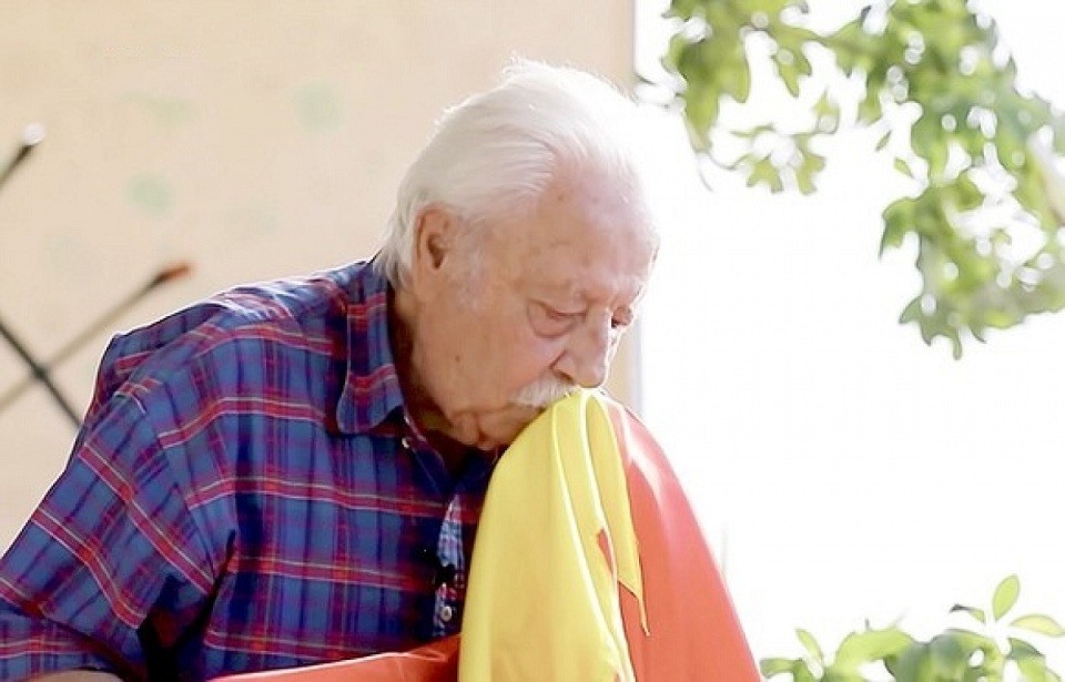 Ông Nguyễn Văn Lập cúi đầu hôn lá cờ đỏ sao vàng một cách trân trọng, nâng niu trong lần trở về Việt Nam năm 2013. (Nguồn: Phim tài liệu)