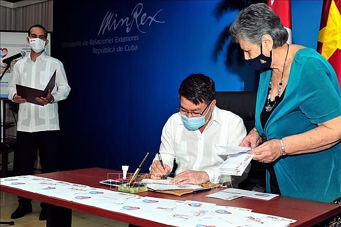 Đại sứ Lê Thanh Tùng kí bì thư có dán tem mới phát hành. (Nguồn: TTXVN)