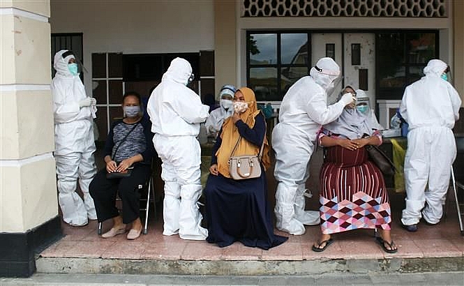Nhân viên y tế lấy mẫu dịch xét nghiệm COVID-19 cho người dân tại Surabaya, Indonesia, ngày 8/12. (Nguồn: TTXVN)