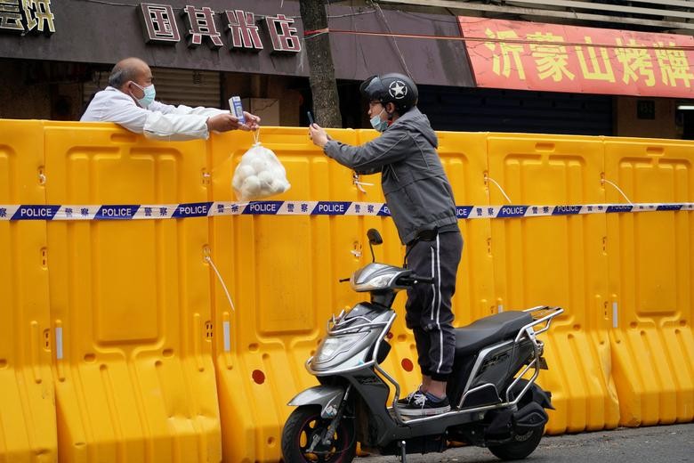 Người đàn ông đứng trên chiếc xe máy quét mã QR để mua thực phẩm từ một người bán hàng tại khu vực bị phong tỏa ở Thượng Hải, Trung Quốc, ngày 30/3. Thành phố sầm uất của Trung Quốc đang trải qua đợt phong tỏa diện rộng nhằm ngăn chặn sự lây lan của dịch 