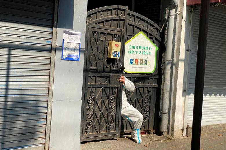 Người dân mặc đồ bảo hộ chui qua cổng một căn nhà, trong đợt bùng phát dịch Covid-19 mạnh nhất từ trước đến nay ở Thượng Hải, Trung Quốc, ngày 21/4. (Nguồn: Reuters)