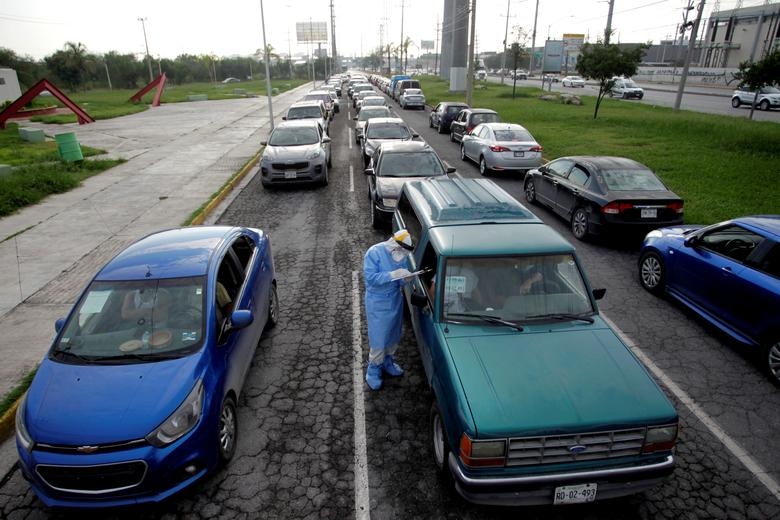 Nhân viên y tế trong bộ đồ bảo hộ cá nhân kiểm tra sức khỏe của người dân tại một địa điểm xét nghiệm lái xe qua đường ở Escobedo, ngoại ô Monterrey, Mexico, ngày 5/8 trong bối cảnh các ca mắc mới Covid-19 đang tăng cao trên khắp cả nước. (Nguồn: Reuters)
