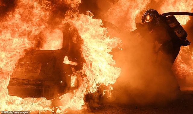 Cận cảnh người lính cứu hỏa đang dập lửa trên chiếc xe cháy dữ dội.